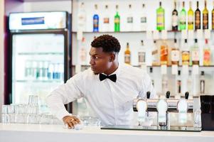 afrikansk amerikansk bartender slitage på fluga rengöring bar. foto