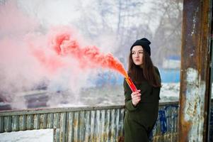 ung flicka med röd färgad rökbomb i handen. foto