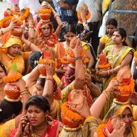 New Delhi, Indien 3 april 2022 - kvinnor med kalash på huvudet under jagannath-templet mangal kalash yatra, indiska hinduistiska hängivna bär jordkrukor som innehåller heligt vatten med en kokosnöt på toppen foto