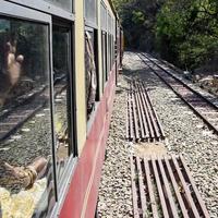 leksakståg rör sig på bergssluttningar, vacker utsikt, ena sidan berg, ena sidan dalen rör sig på järnväg till kullen, bland grön naturskog. leksakståg från kalka till shimla i indien, indiskt tåg foto