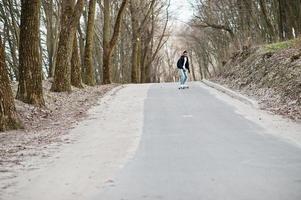 street style arabisk man i glasögon med longboard longboarding på vägen. foto