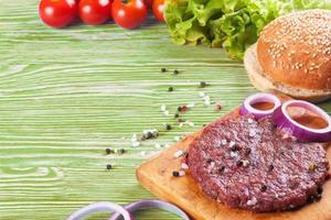 ingredienserna till hamburgaren på grön träbakgrund foto