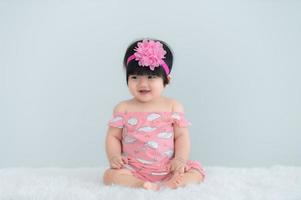 porträtt av söt asiatisk baby på vit matta, nyfödd leende för att ta ett foto