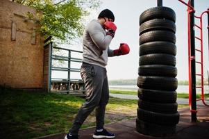 porträtt sport arabisk boxerman i svart medicinsk ansiktsmask boxning utomhus under koronaviruskarantän. foto