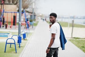 ung tusenårig afrikansk pojke i staden. glad svart man i jeansjacka. generation z koncept. foto