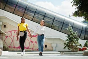 vit kaukasisk flicka och svart afroamerikan tillsammans mot graffitiväggen. världsenhet, raskärlek, förståelse i tolerans och samarbete mellan raser och mångfald. foto