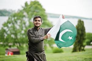 indo pakistansk man bär traditionella kläder achkan eller sherwani med pakistansk flagga. foto