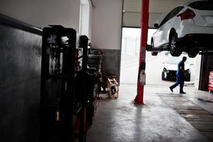 bil reparation och underhåll tema. mekaniker i uniform arbetar inom bilservice. foto