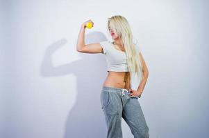 blond sportig tjej med gul hantel poserade i studio mot vit bakgrund. foto