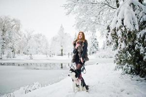 rödhårig tjej går i parken med husky hund på vinterdagen. foto