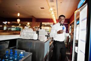 afroamerikansk bartender i baren som tar energidryck från kylskåpet. foto