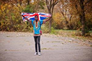 afrikansk man i Afrika traditionell skjorta på höstparken med Storbritanniens flagga. foto