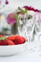 jordgubbar, champagnerflöjt och blommor foto