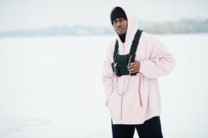 elegant urban stil afrikansk amerikansk man i rosa hoodie poserade vid frusen sjö på vintern. foto