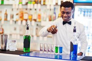 afroamerikansk bartender i baren gör cocktails på skott. beredning av alkoholhaltiga drycker. foto