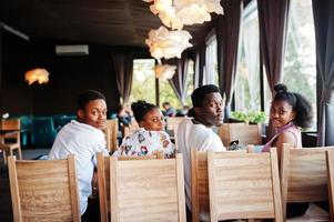glada afrikanska vänner sitter och chattar på café. grupp av svarta folk som möter i restaurangen. foto