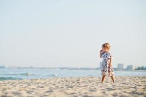 dotter ha kul på stranden. porträtt av glad söt liten flicka på semester. foto