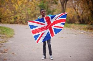 afrikansk man i Afrika traditionell skjorta på höstparken med Storbritanniens flagga. foto