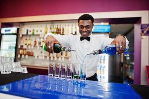 afroamerikansk bartender i baren gör cocktails på skott. beredning av alkoholhaltiga drycker. foto