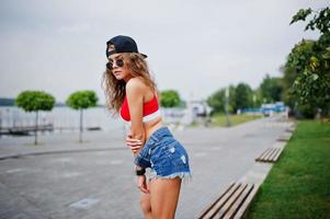 sexig modell tjej i röd topp, jeans jeansshorts visar hennes skinkor. foto