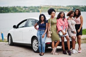 grupp av fem glada afroamerikanska tjejer poserade mot bilen. foto