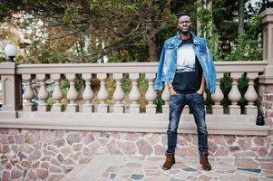 ung attraktiv seriös afrikansk amerikansk man modell. modern stilig kille i jeansjacka som står på stadsgatan. foto