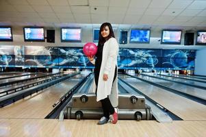 snygg asiatisk kvinna som står vid bowlinghall med boll till hands. foto