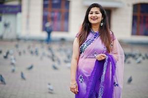 indisk hinduisk flicka på traditionell violett saree poserade på gatan mot duvor. foto