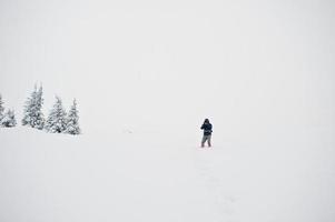 man turistfotograf med ryggsäck, vid berg med tallar täckta av snö. vackra vinterlandskap. frost natur. foto