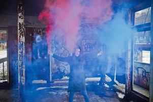 ung flicka med blå och röd färgade rökbomb i händerna. foto