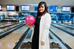 snygg asiatisk kvinna som står vid bowlinghall med boll till hands. foto