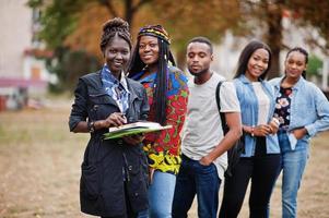 rad av grupp fem afrikanska högskolestudenter tillbringar tid tillsammans på campus på universitetsgården. svarta afro vänner studerar. utbildningstema. foto