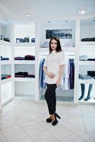 brunett vacker flicka i klädbutik boutique på casual kläder, vit blus och svarta byxor. foto