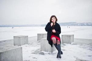 brunett plus size modell på rött mot frusen sjö på vinterdagen. foto