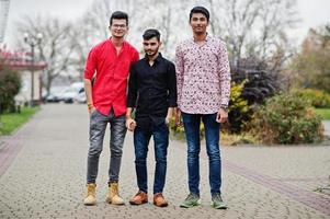 tre indiska killar studenter vänner går på gatan. foto