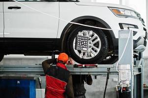 amerikansk suv-bil på stativ för hjulinställning camber check i verkstaden på bensinstationen. foto