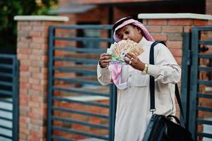 Mellanöstern arabisk affärsman poserade på gatan mot modern byggnad med svart handväska och europengar. foto