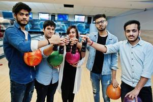 grupp av fem sydasiatiska folk som har vila och roligt på bowlingklubben. klirrande kalla läskdrycker från glasflaskor och bowlingklot vid händerna. foto