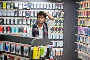 indisk man kund köpare på mobiltelefon butik välj ett fodral för sin smartphone. sydasiatiska folk och teknik koncept. mobiltelefon butik. foto