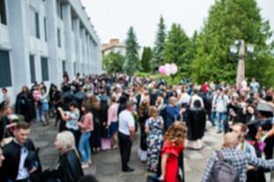 suddigt foto av akademiker och deras föräldrar eller vänner väntar på balceremonin utanför.