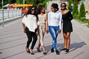 grupp av fyra afroamerikanska flickor går på staden på solig dag. foto