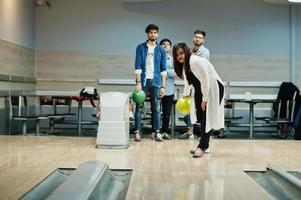 sydasiatisk kvinna står vid bowlinghall med boll på händerna. flickan förbereder sig för ett kast. foto