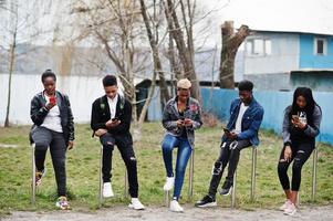 unga millennials afrikanska vänner med mobiltelefoner. glada svarta människor som har roligt tillsammans. generation z vänskap koncept. foto
