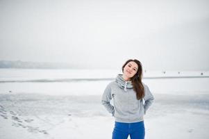 rolig tjej slitage på hoody tröja och jeans, vid frusen sjö i vinterdag. foto