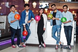 grupp av fem sydasiatiska folk som har vila och roligt på bowlingklubben med bollar vid händerna. foto