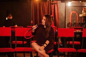 asiatisk tjej röker vattenpipa i loungebaren. foto