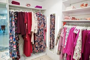 kvinnliga rosa färgglada kläder set på hyllorna och hyllorna i klädaffären helt ny modern boutique. vårens sommarklänningskollektioner. foto