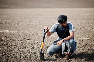 sydasiatisk agronombonde med spade som inspekterar svart jord. jordbruksproduktion koncept. foto