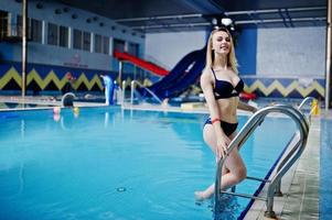 sexig blond flicka i blå baddräkt med vila i poolen i vattenparken. foto