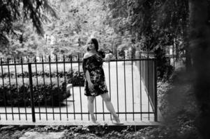 porträtt av en flicka i en klänning poserar vid staketet. foto